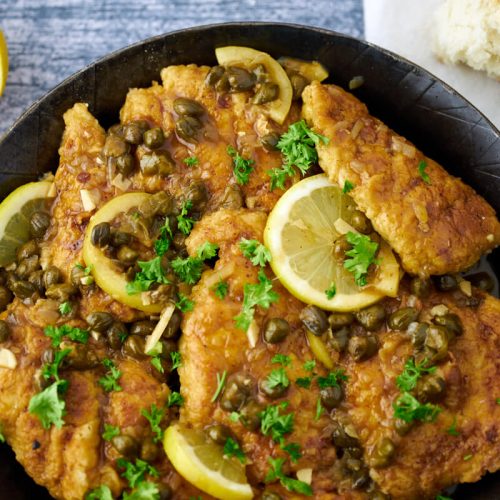 chicken piccata in pan with capers, lemon and parsley