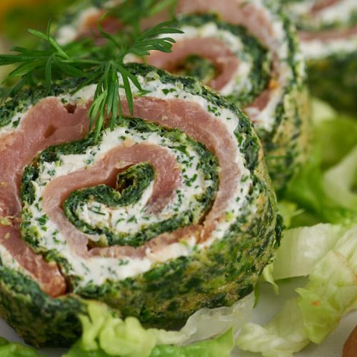 Spinach roulade with smoked salmon and cream cheese filling served with dill, lemon, lettuce and bread