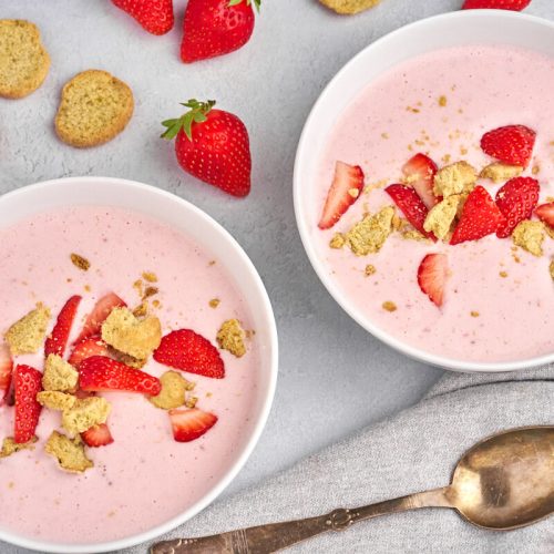 two bowls with danish cold strawberry buttermilk soup with fresh strawberries and kammerjunkere
