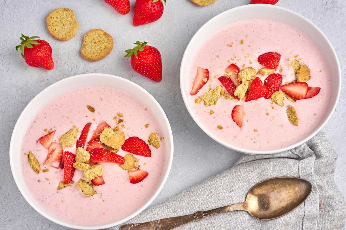 two bowls with danish cold strawberry buttermilk soup with fresh strawberries and kammerjunkere