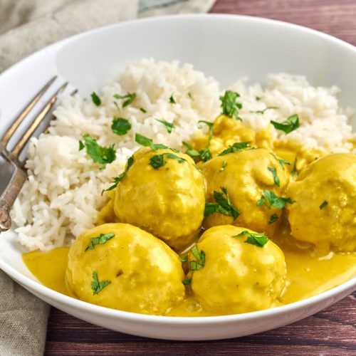 danish meatballs in curry or boller i karry in a white plate served with rice