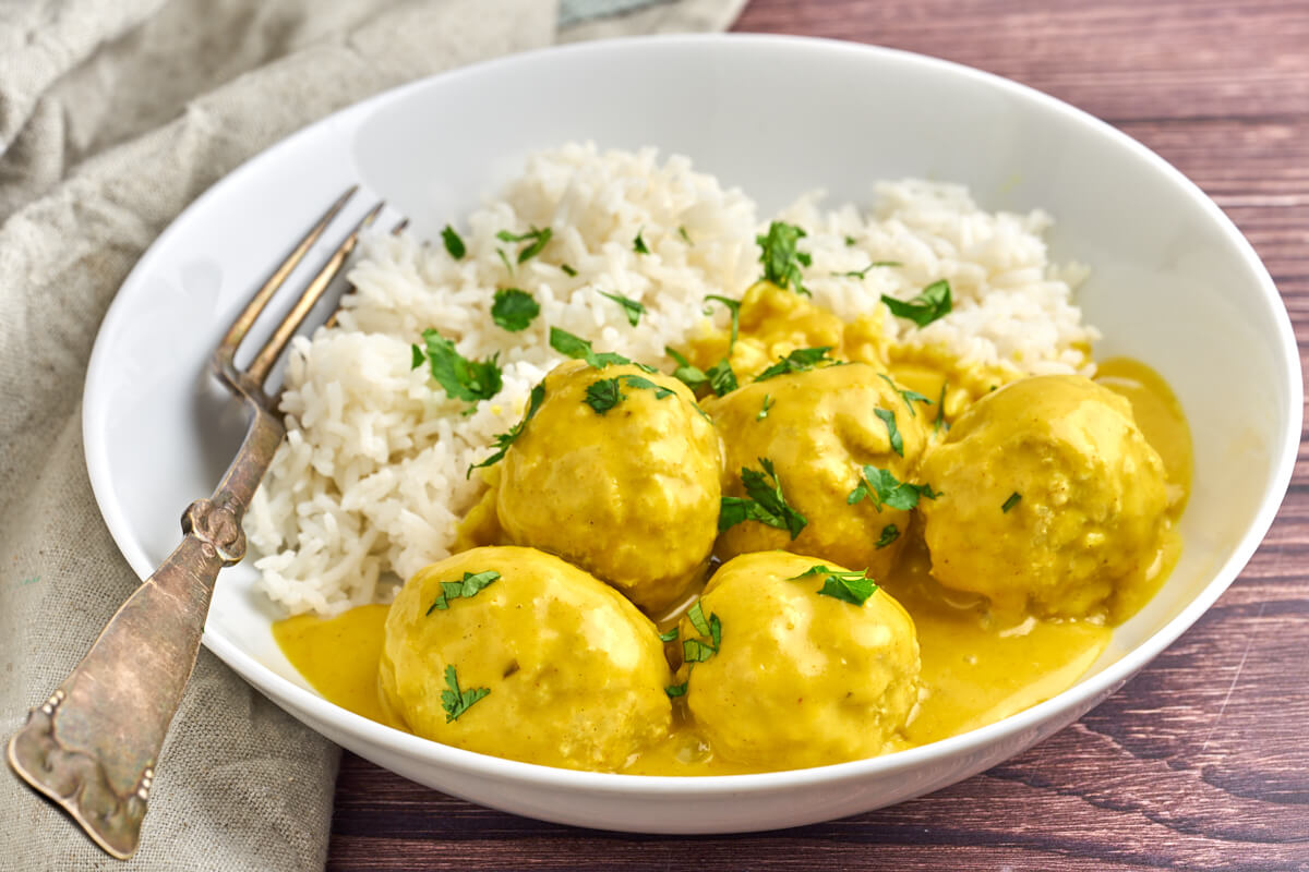 danish meatballs in curry or boller i karry in a white plate served with rice