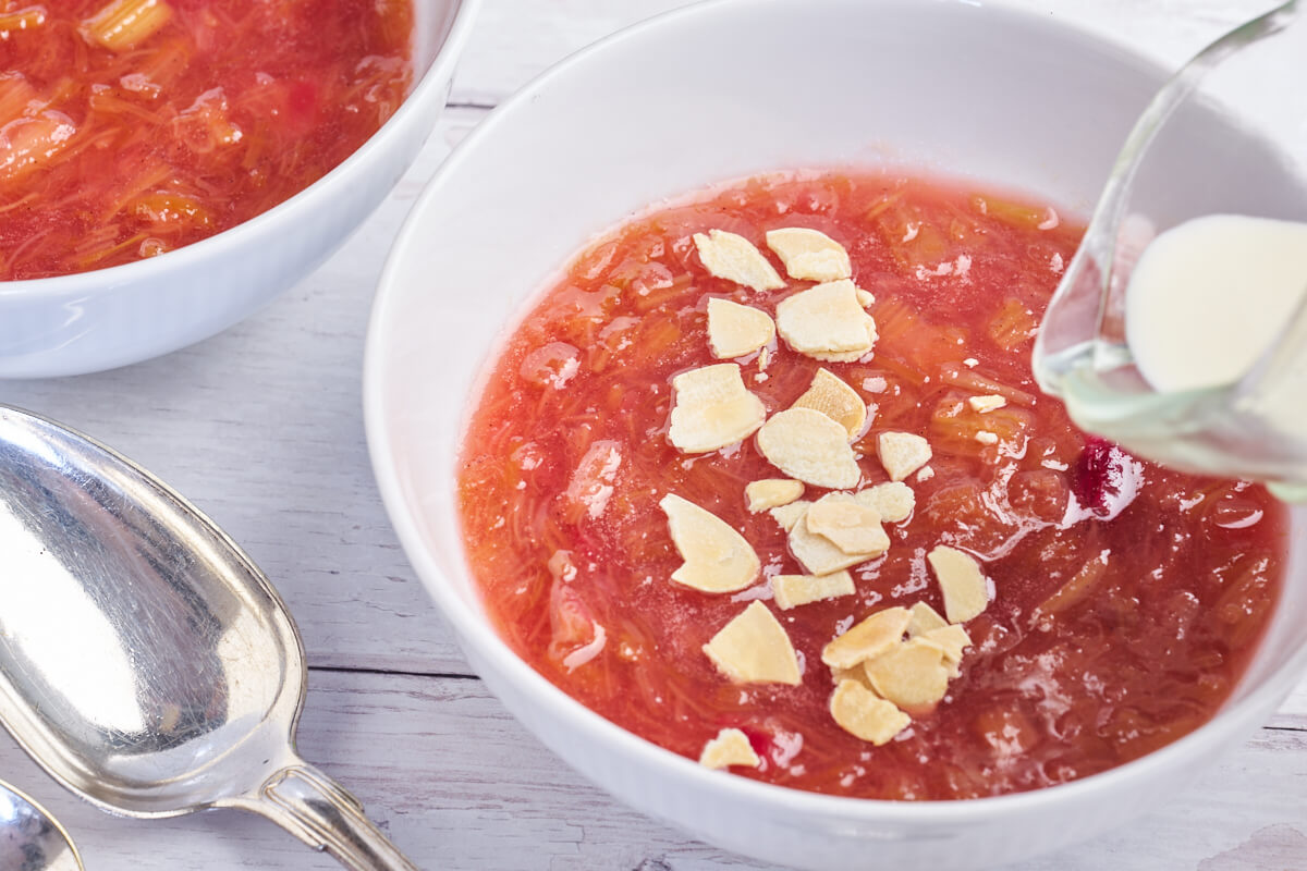 bowl of rhubarb pudding with almond flakes and cream