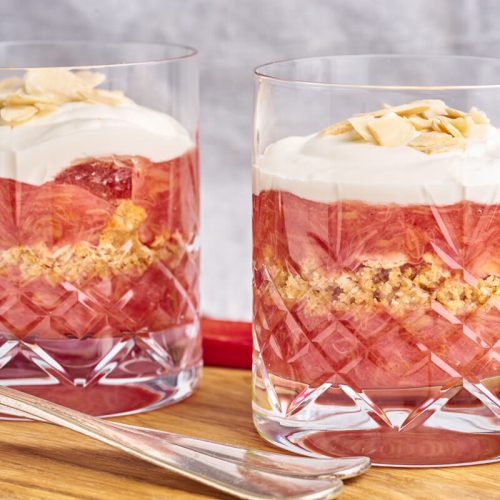 Old-fashioned Danish Rhubarb cake served in glasses with whipped cream on top