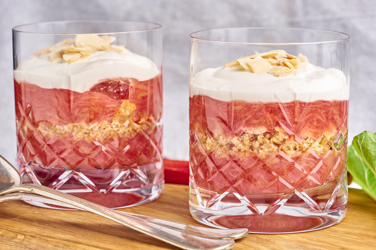 Old-fashioned Danish Rhubarb cake served in glasses with whipped cream on top