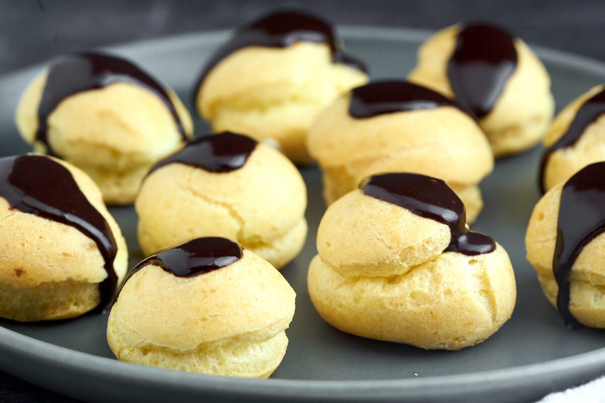 plate with small profiteroles with pastry cream and chocolate icing