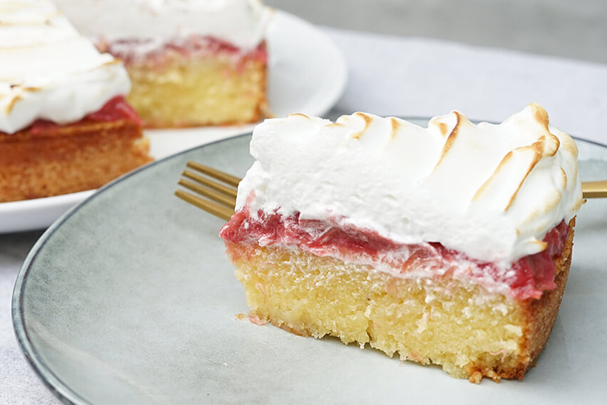 slice of rhubarb meringue cake and the whole cake in the back