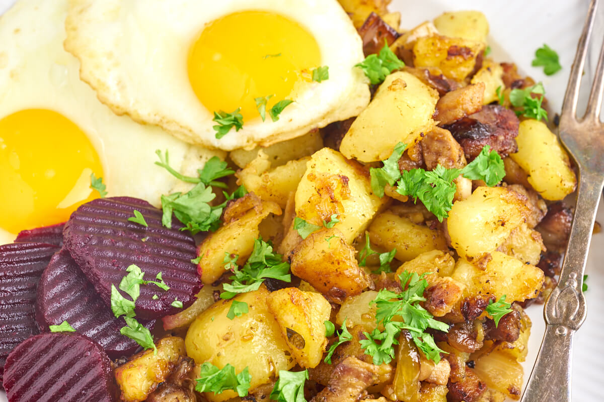 Danish hash with potatoes and pork served with fried eggs and pickled beets