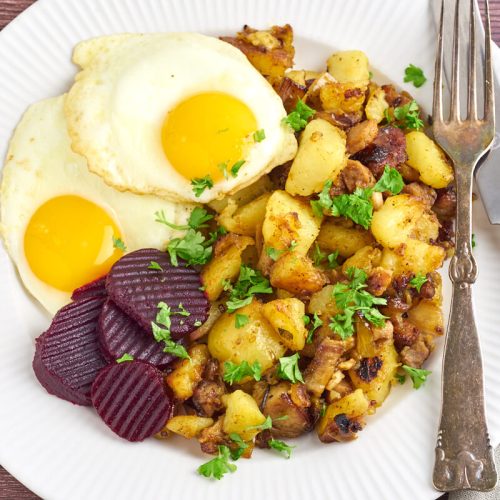 danish hash with potatoes and pork served with fried eggs and pickled beets