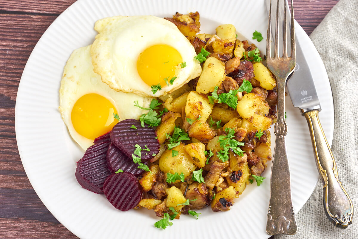 danish hash with potatoes and pork served with fried eggs and pickled beets