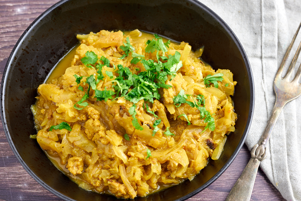 cabbage and chicken curry dish in black bowl