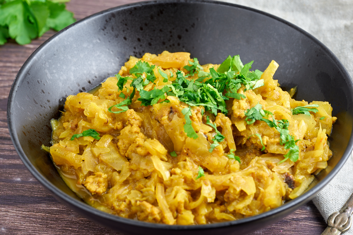 bowl of curried cabbage and chicken with fresh coriander