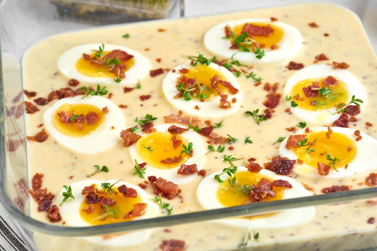 half eggs in mustard sauce with crispy bacon and garden cress