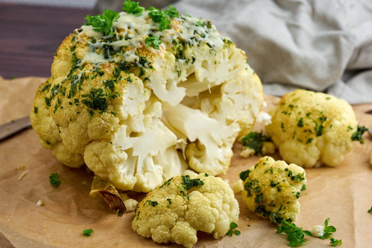 whole roasted cauliflower in oven with parsley, parmesan and lemon