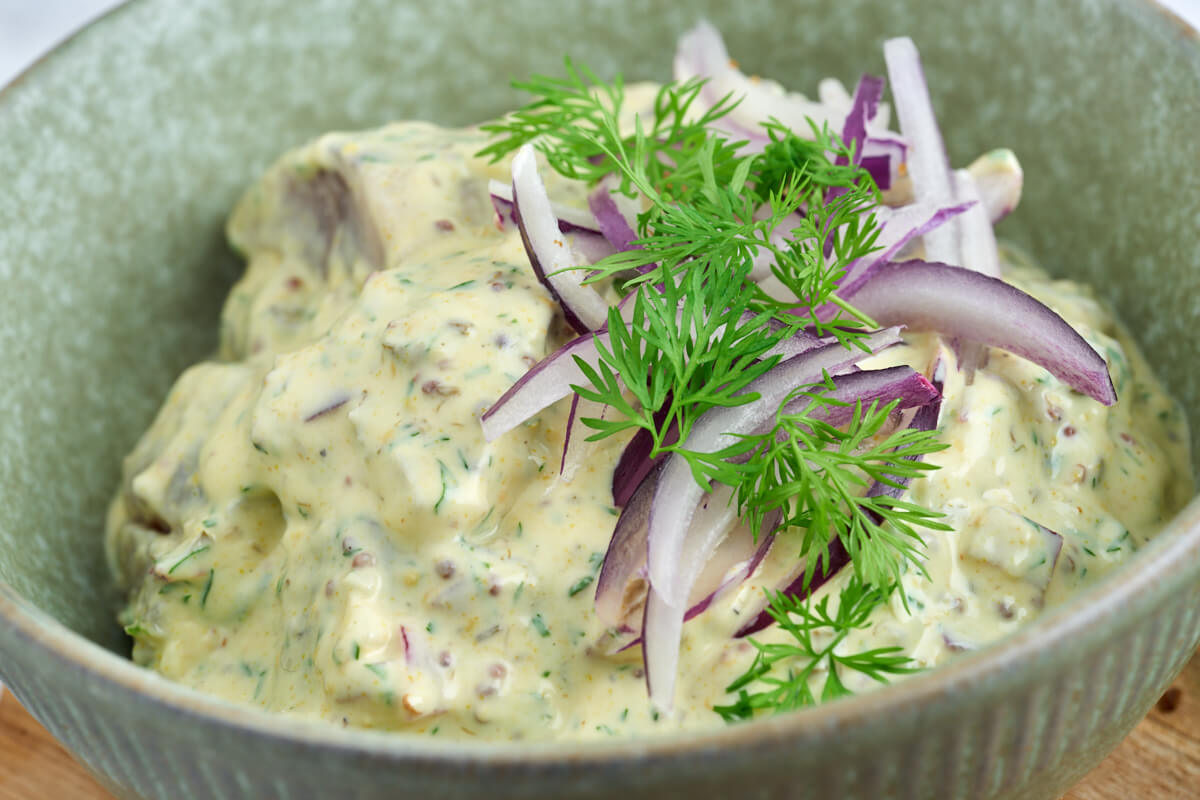 pickled herring in mustard sauce with dill and red onion on top