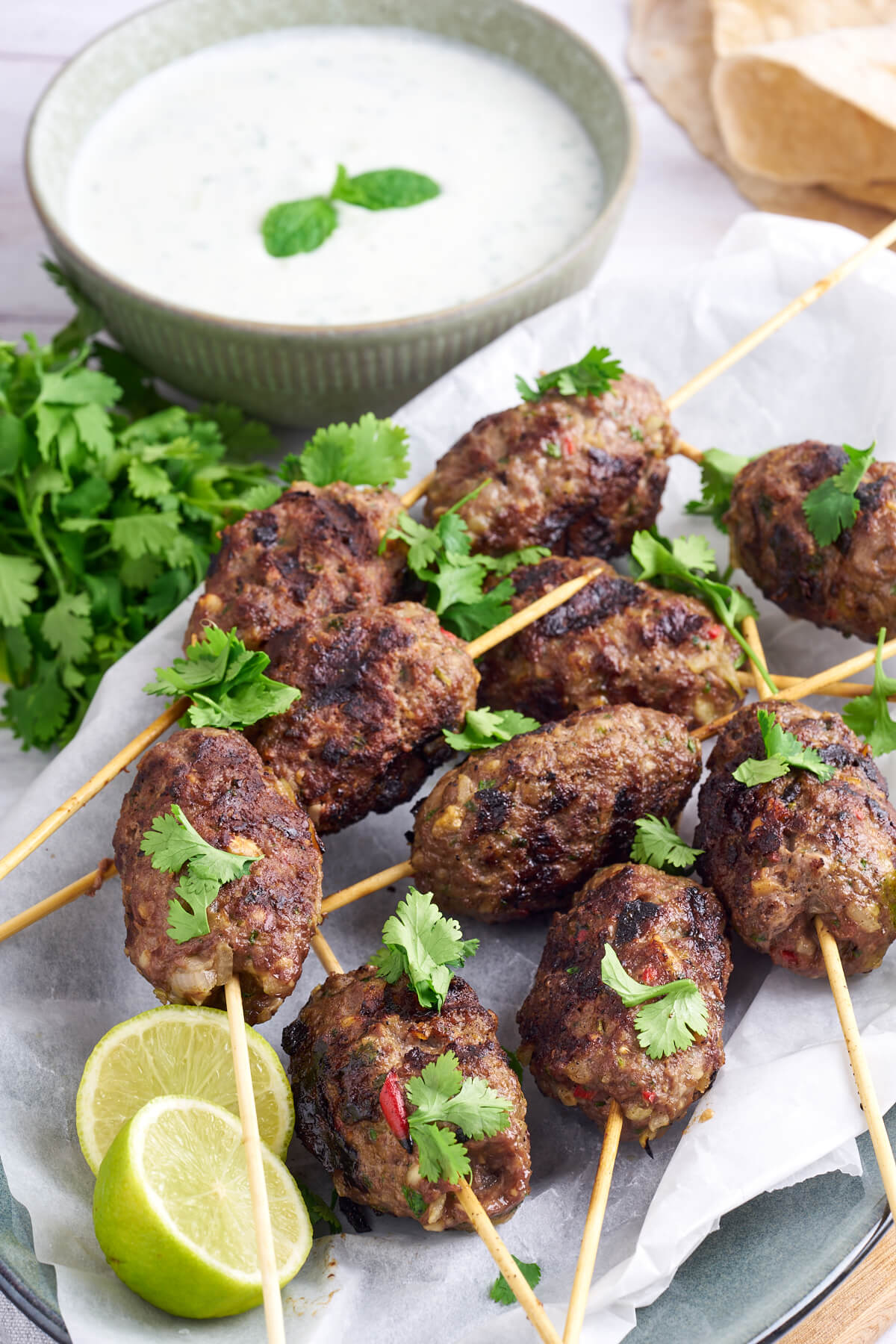 kofta kebabs with cilantro and lime and a bowl of raita