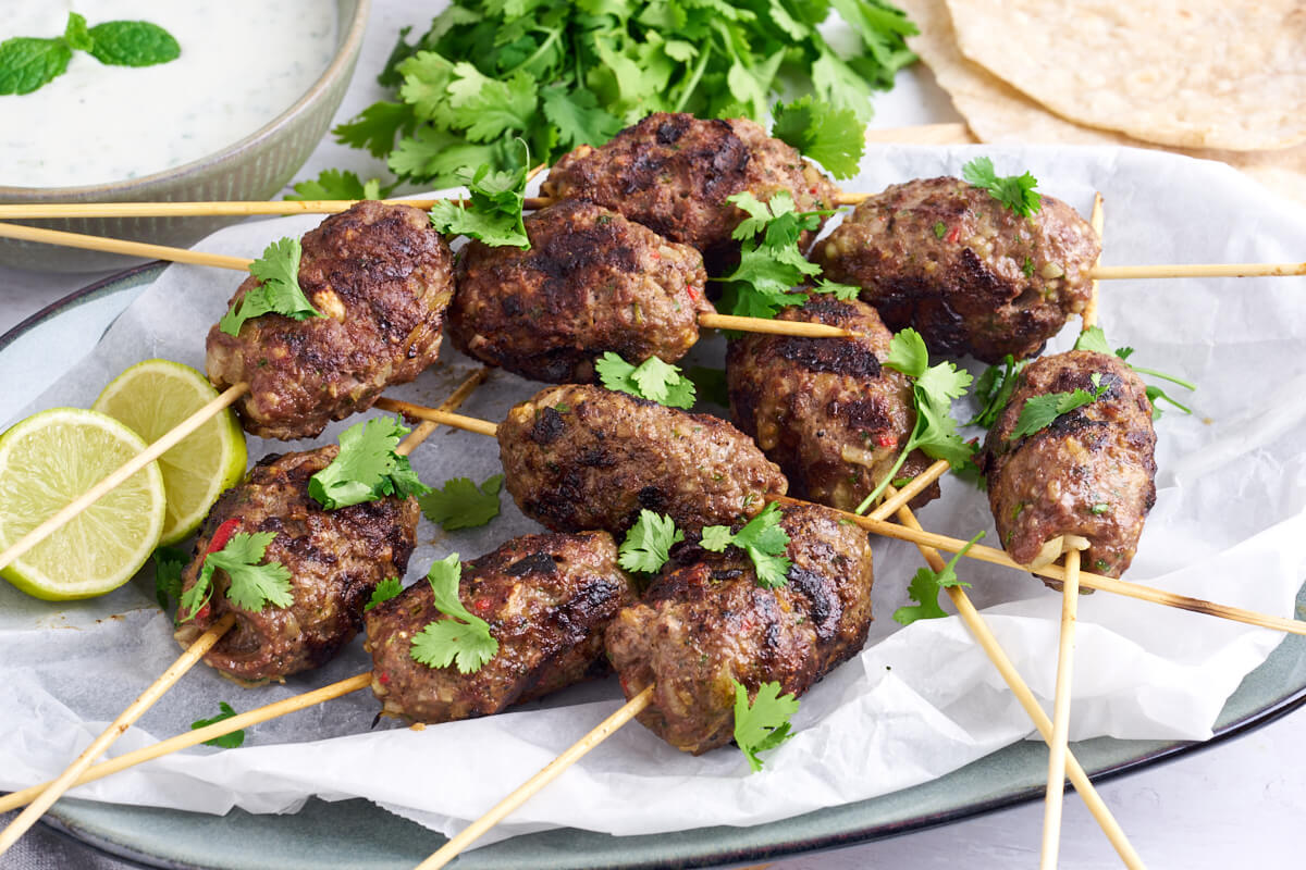 kofta kebab skewers with cilantro served with roti bread and raita