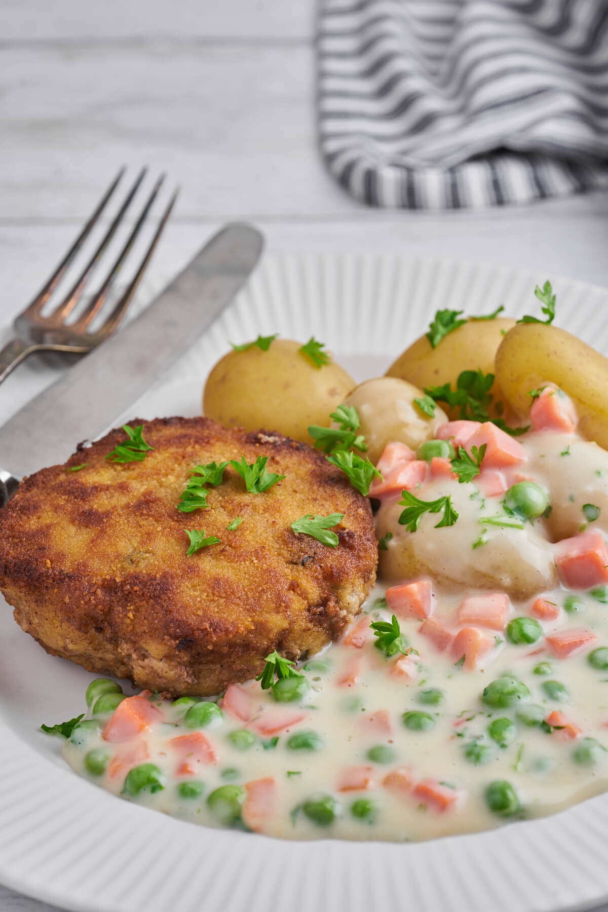 plate with danish breaded pork patties and potatoes with peas and carrot stew