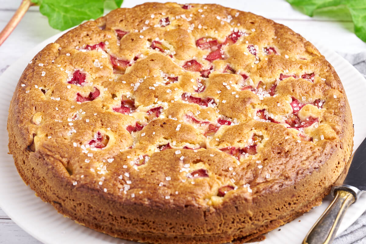 rhubarb cake on plate with knife and rhubarbs