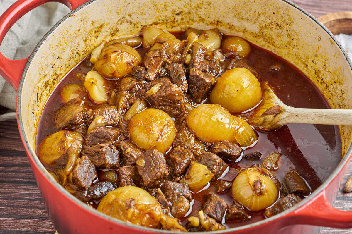 pot with greek beef stifado with wooden spoon