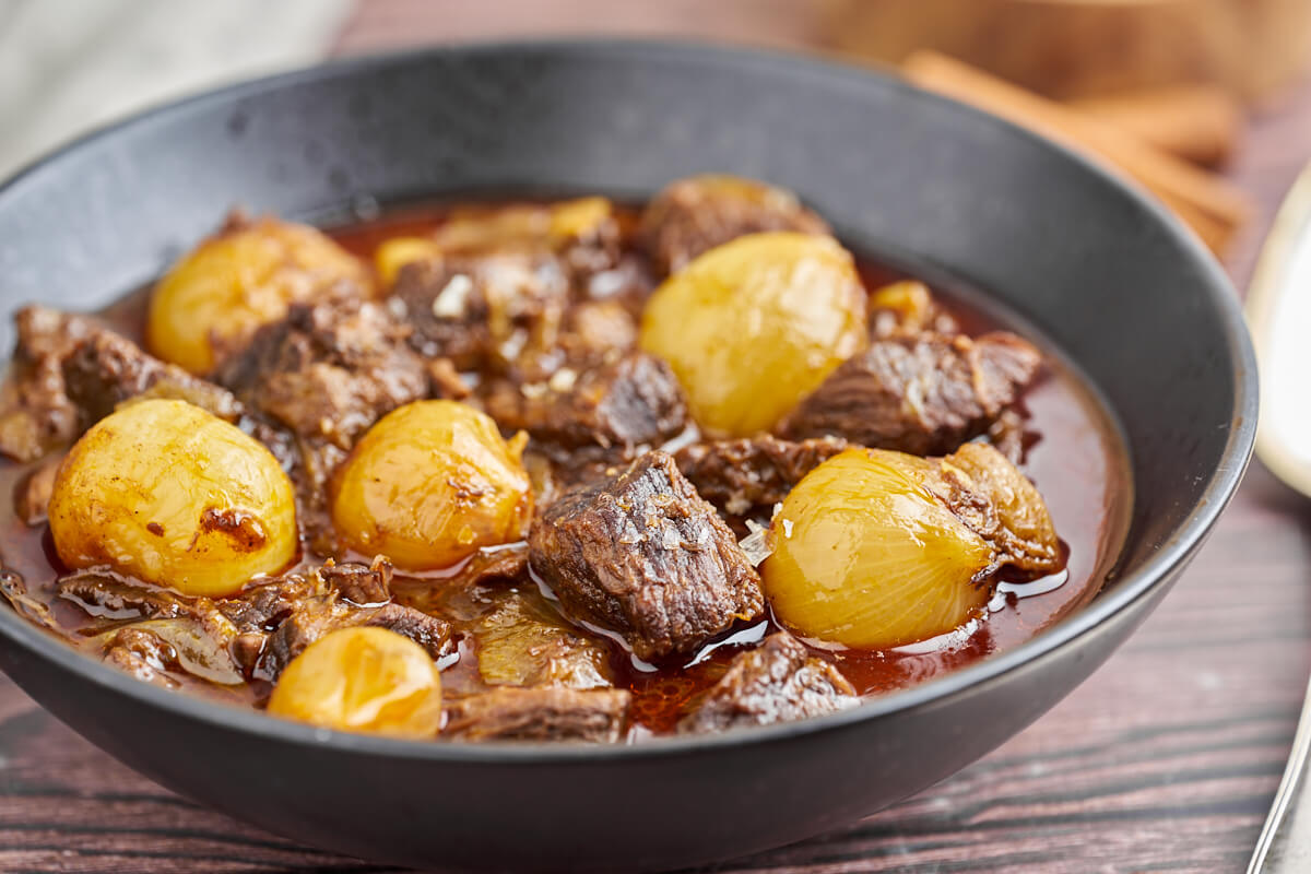 black plate with greek beef stifado with onions