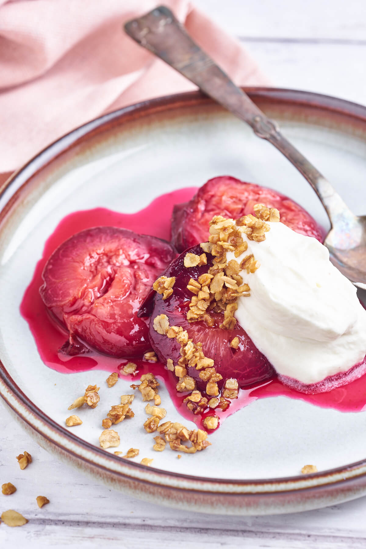 plate with baked plums, crumble and whipped cream