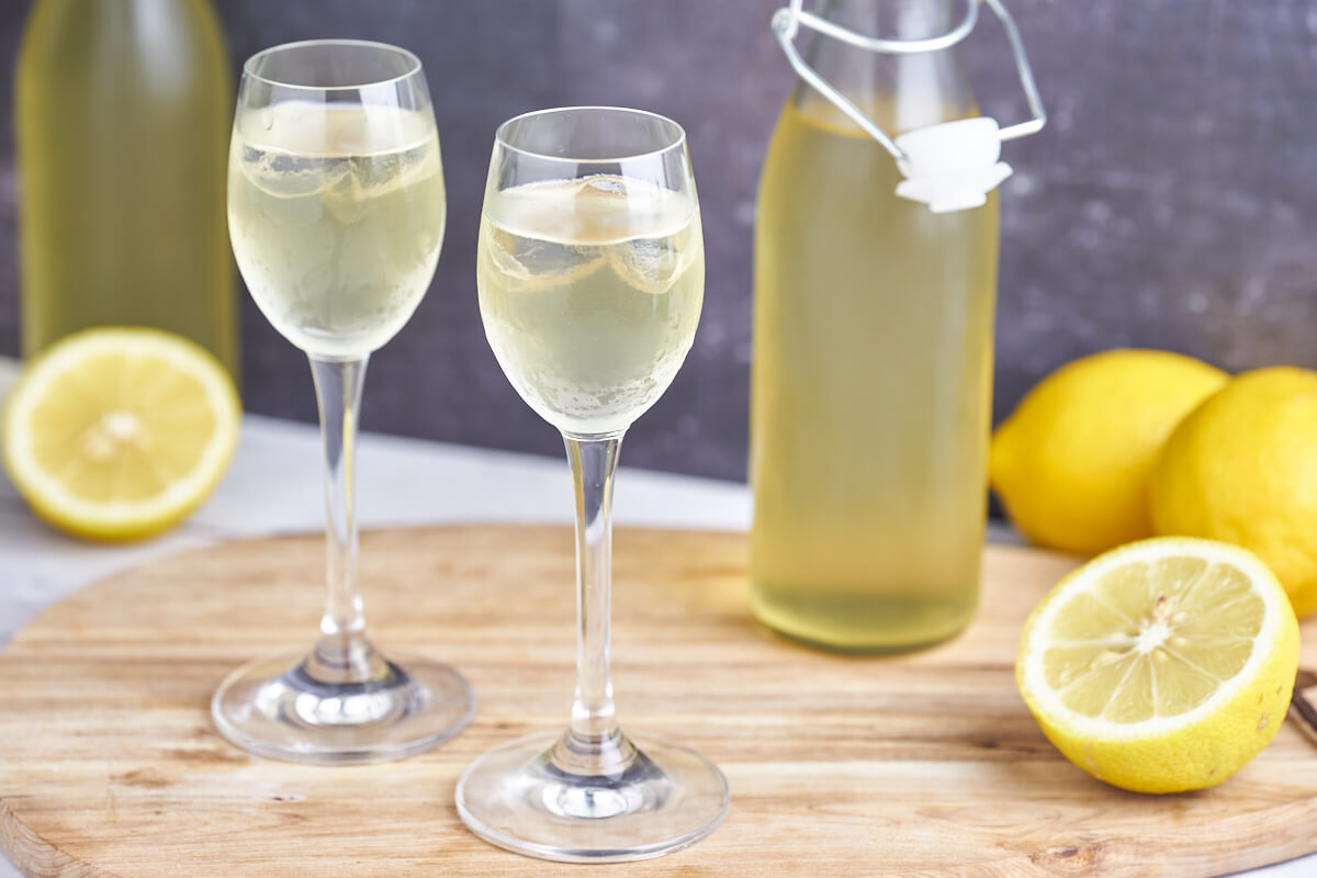 limoncello in tall glasses and lemons and small bottles with the italian lemon liqueur