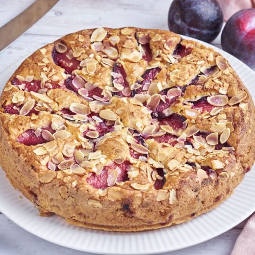 Plum cake on plate with plums and knife