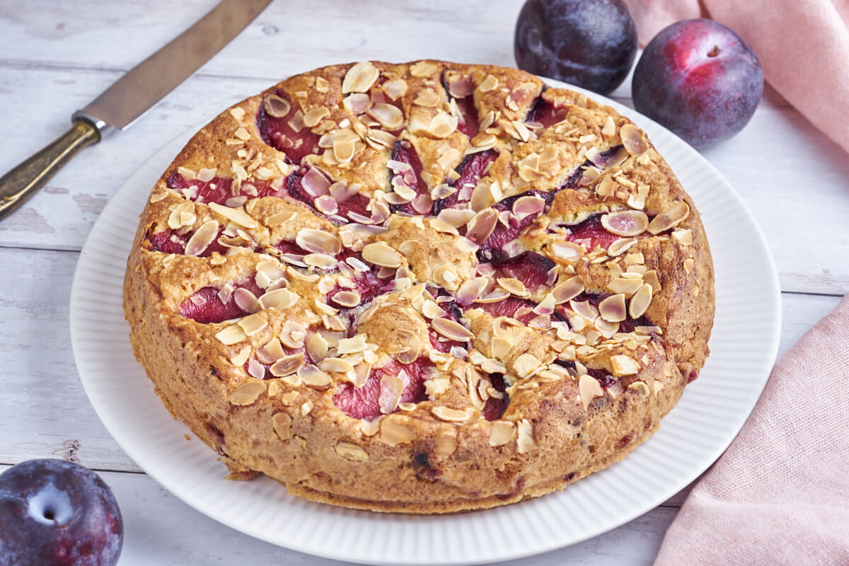 Plum cake on plate with plums and knife