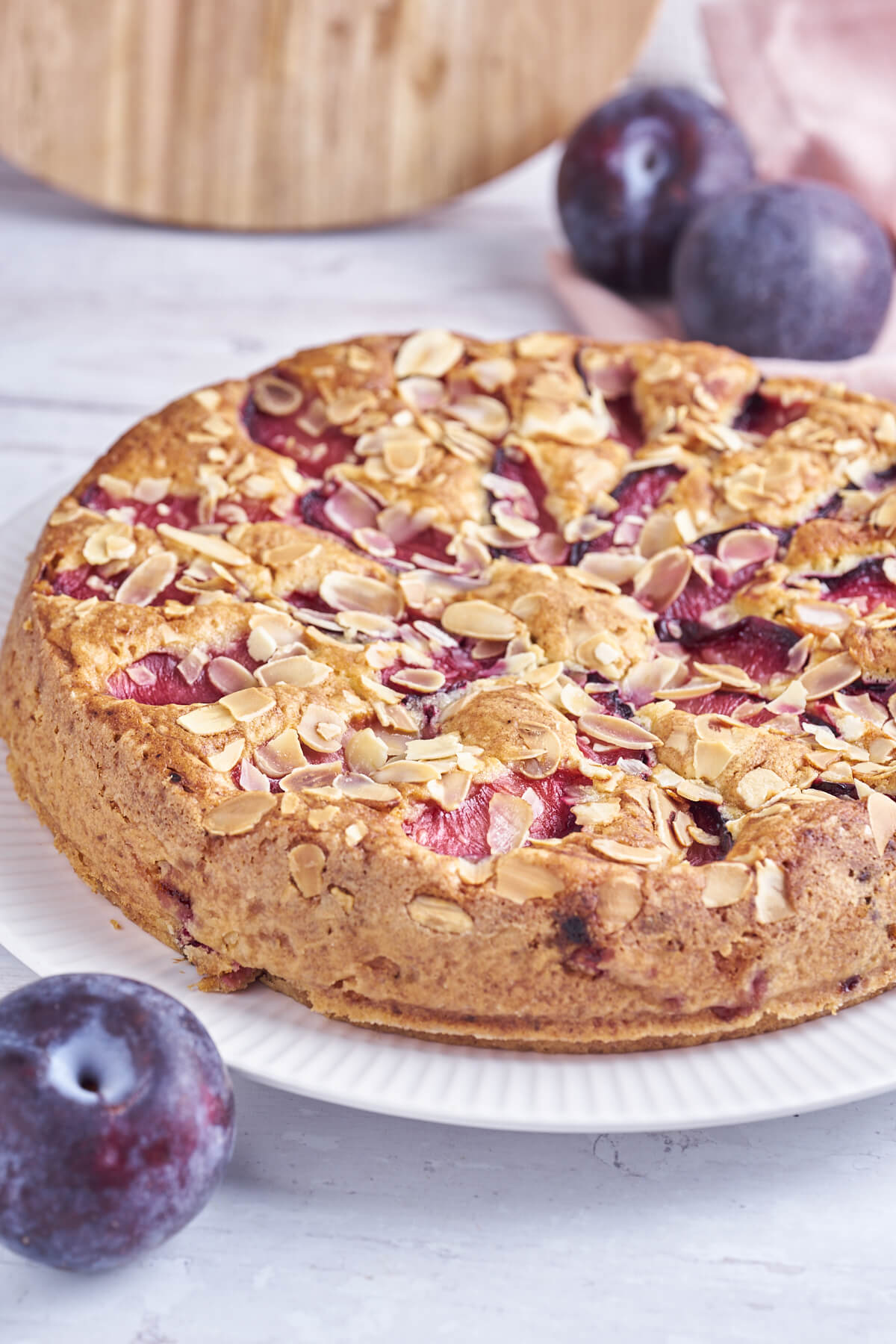 plum cake with almond flakes on plate with fresh plums