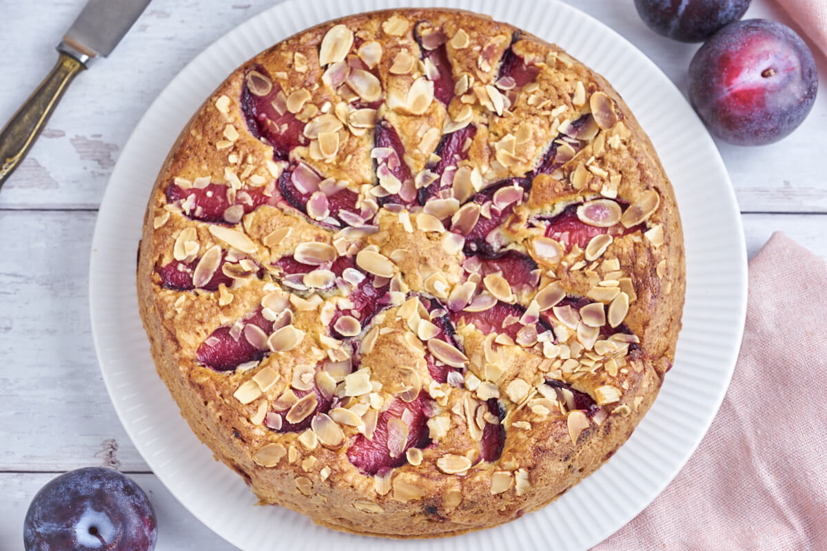 plum cake on a white plate with fresh plums