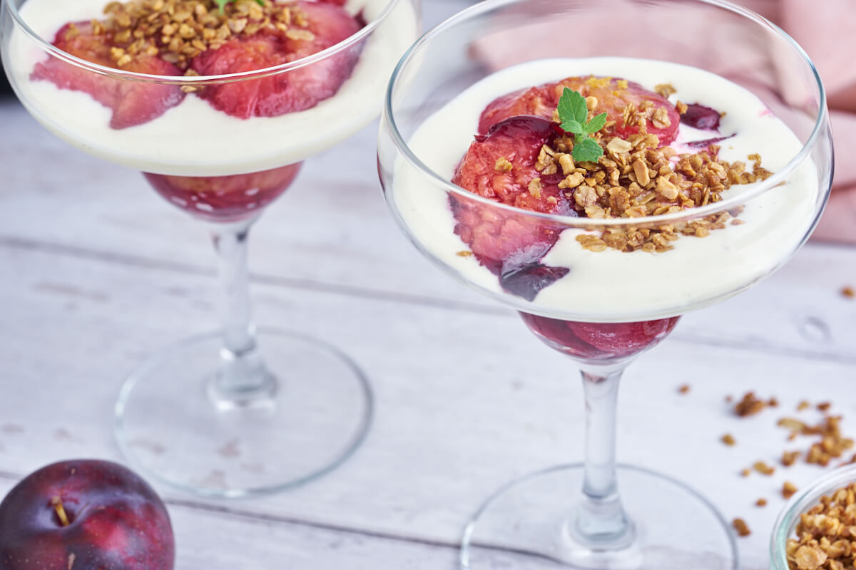 glass with plum trifle with baked plums, oatmeal crunch and vanilla cream