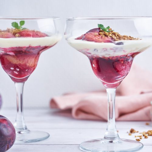 two glasses with plum trifle with crumble and vanilla cream