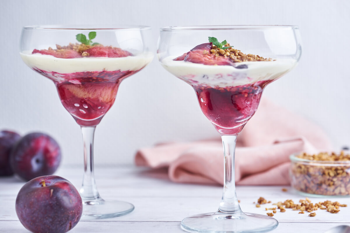 two glasses with plum trifle with crumble and vanilla cream