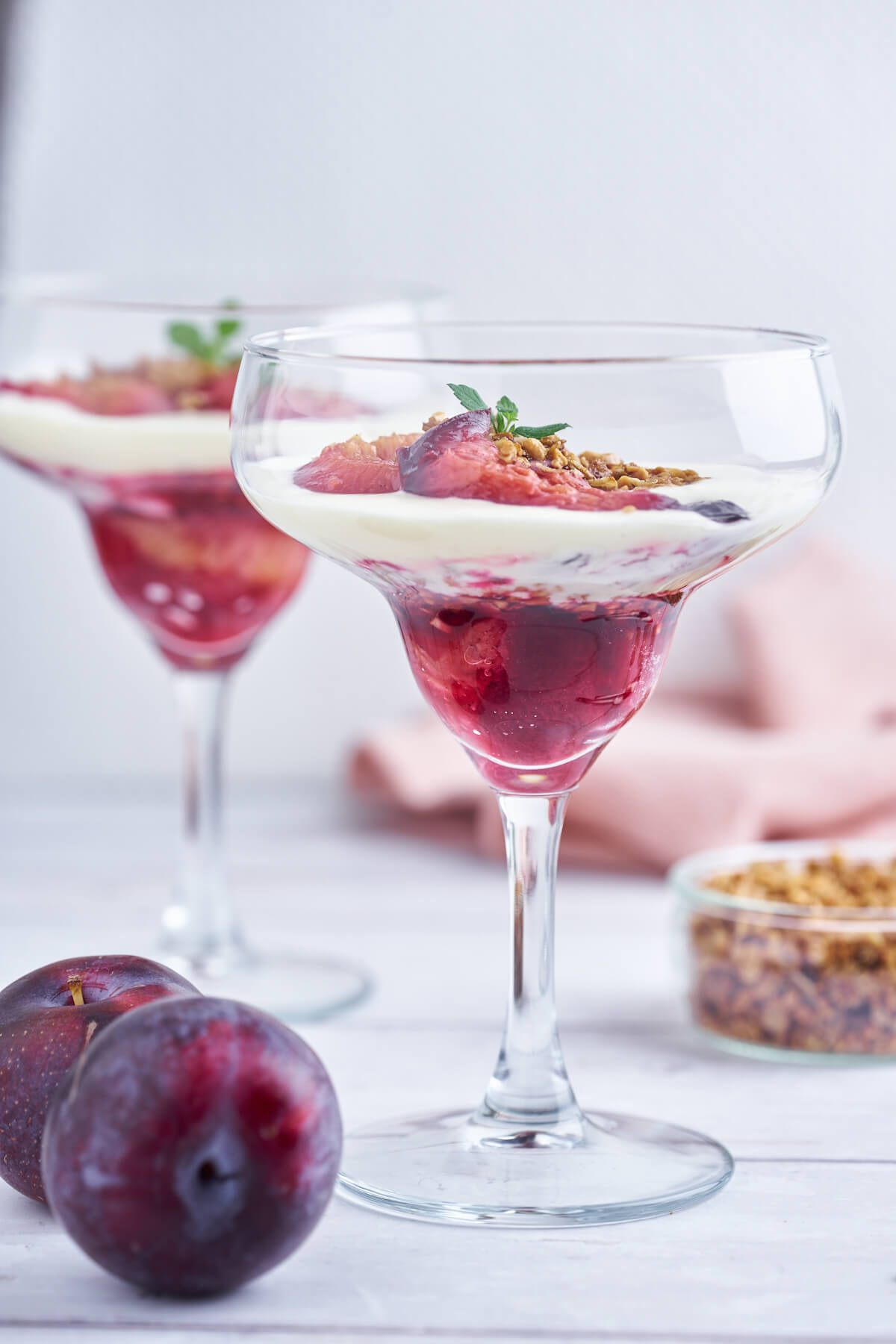 plum trifle in glasses with crumble, baked plums, and vanilla cream