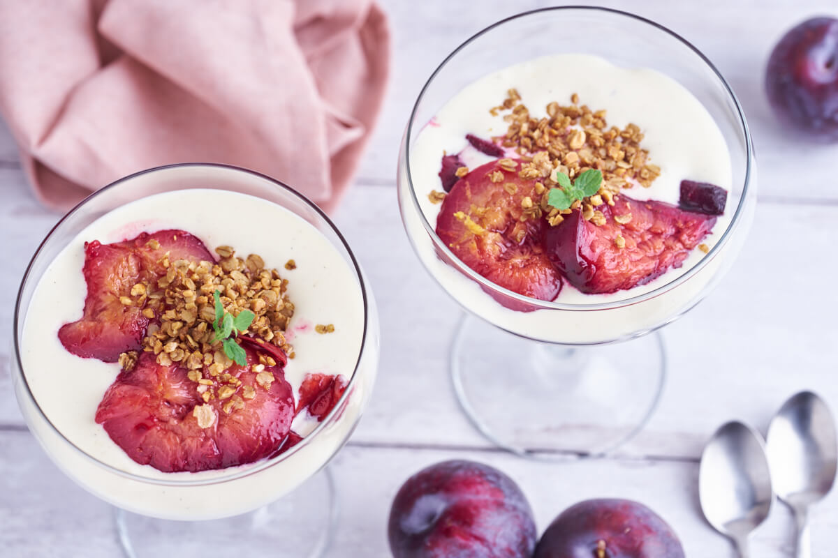 plum trifle in glasses with baked plums, vanilla cream and oatmeal crumble