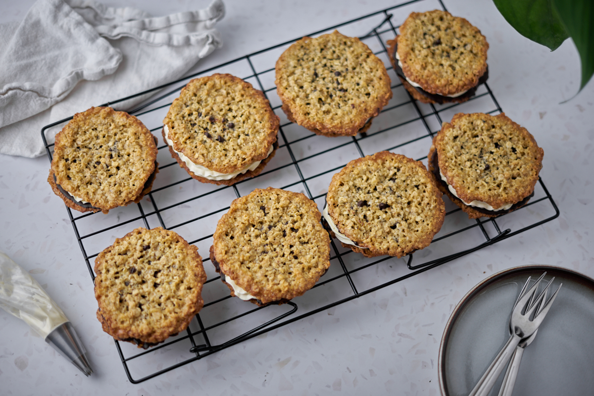 rack woth oatmeal cookies with buttercream and plates next to it