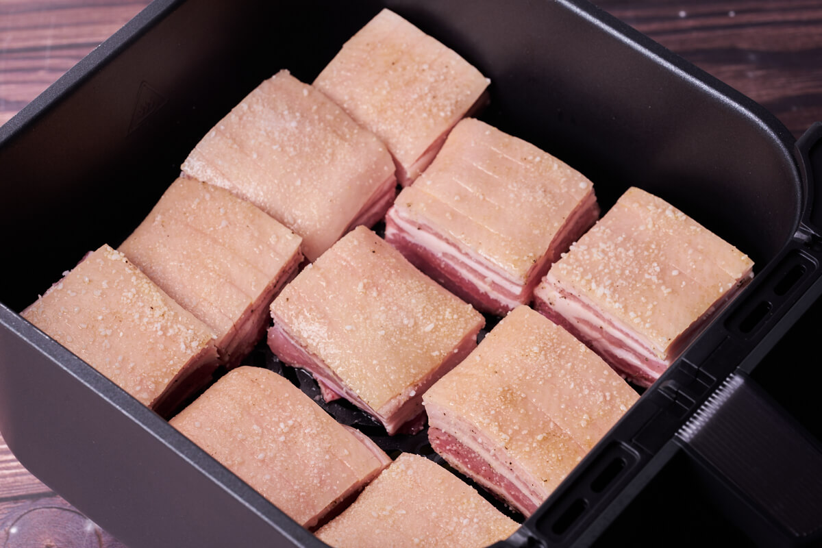 raw pork belly pieces in air fryer basket