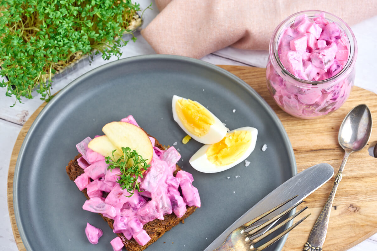 plate with rye bread topped with danish herring salad, apple and cress