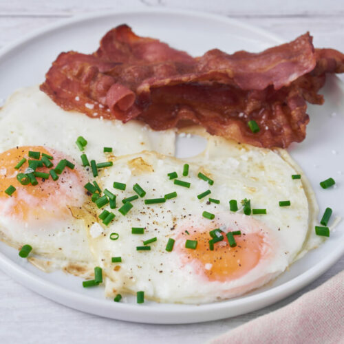 air fryer fried eggs on plate with bacon