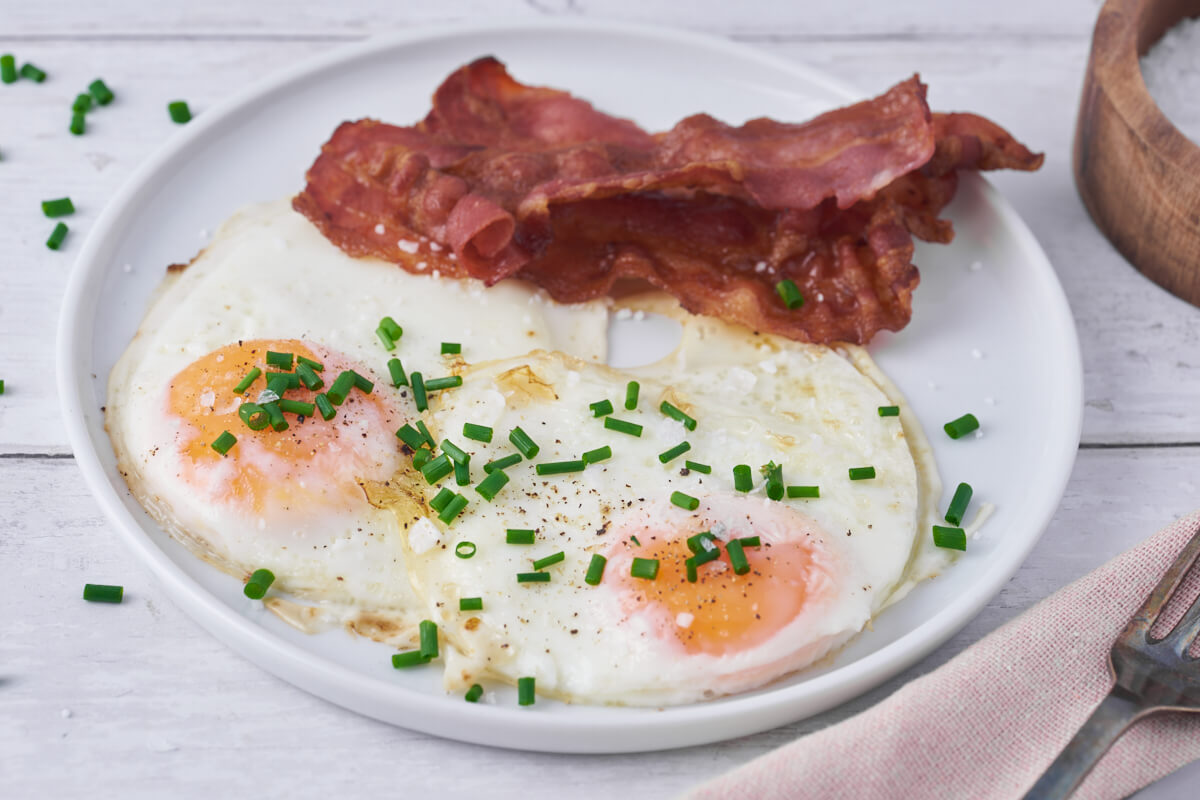 air fryer fried eggs on plate with bacon