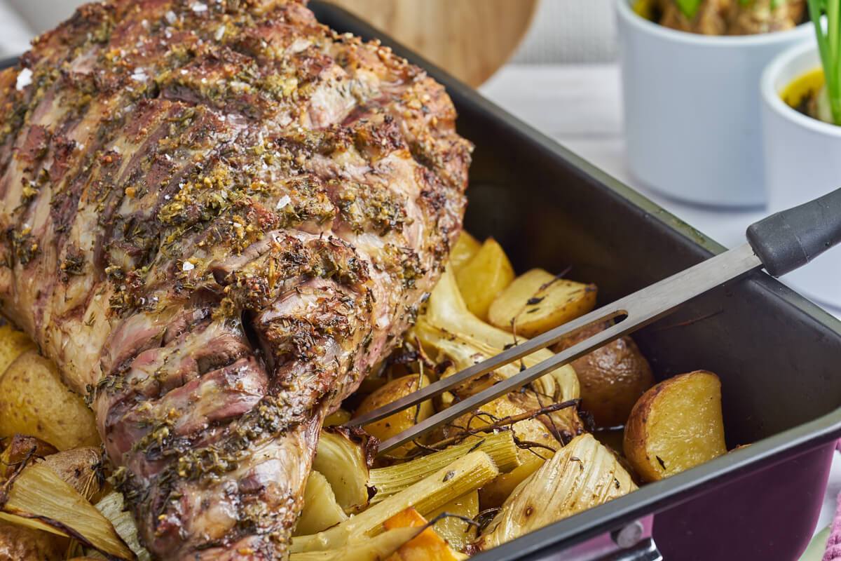 potatoes in dish with leg of lamb on top