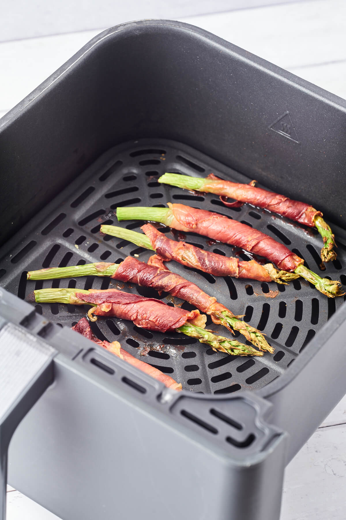 air fryer basket with prosciutto wrapped asparagus