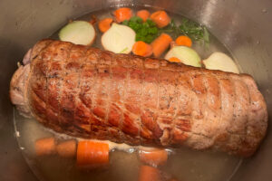 rolled roast in a pot with vegetables and stock