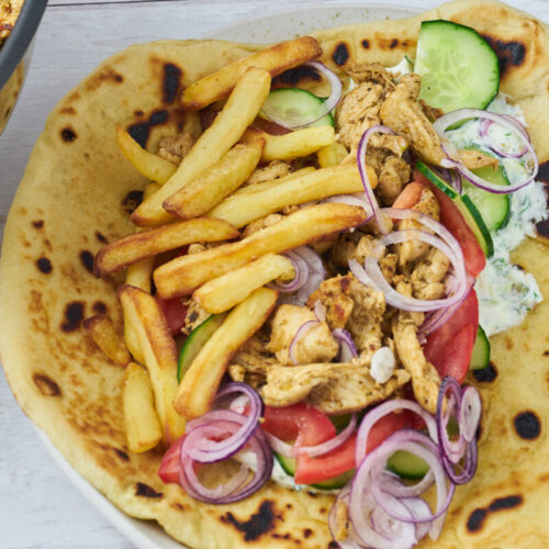 greek chicken gyros with french fries, greens and tzatziki in flatbreads