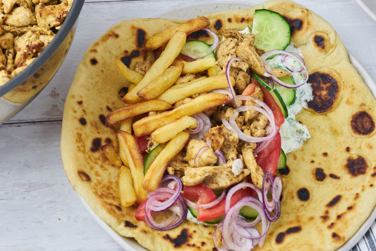 greek chicken gyros with french fries, greens and tzatziki in flatbreads