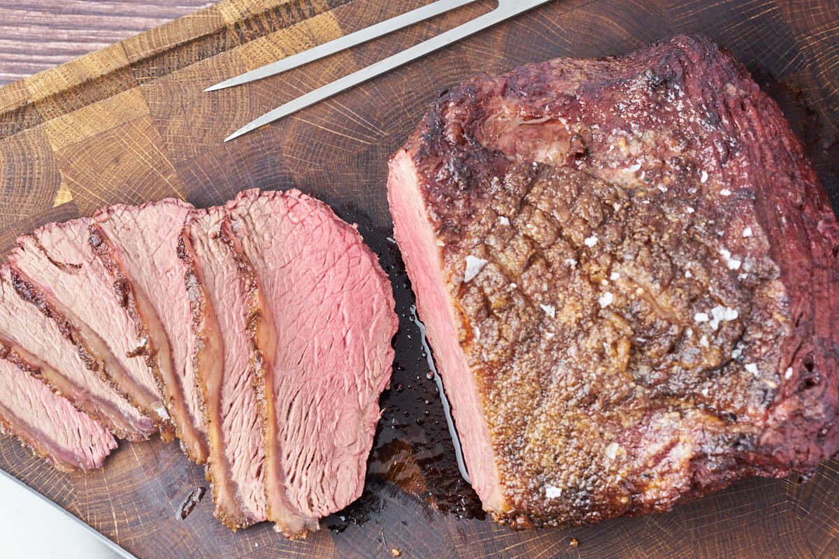 grilled top sirloin cap roast sliced on cutting board