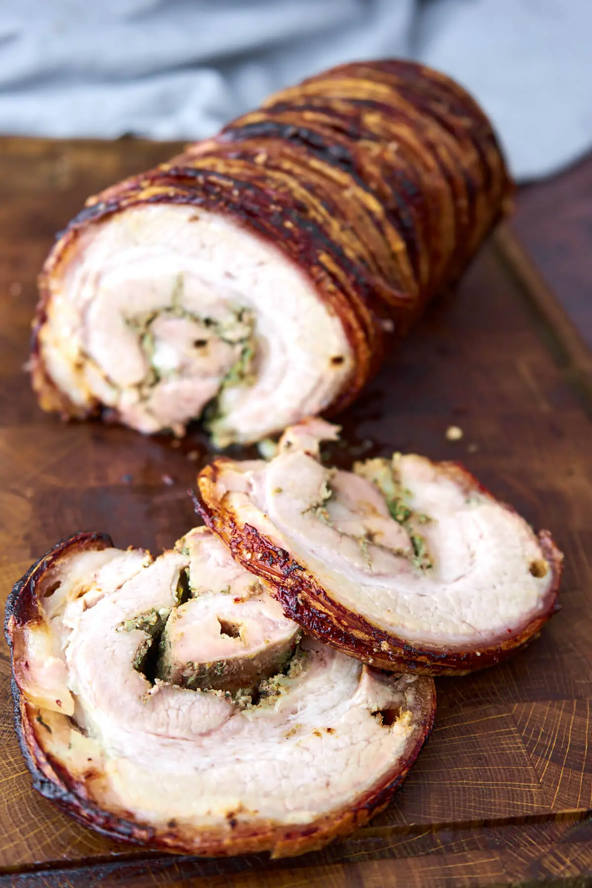 Italian porchetta on wooden cutting board with slices