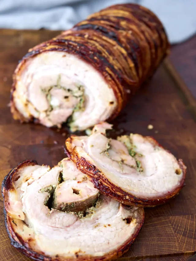 Italian porchetta on wooden cutting board with slices