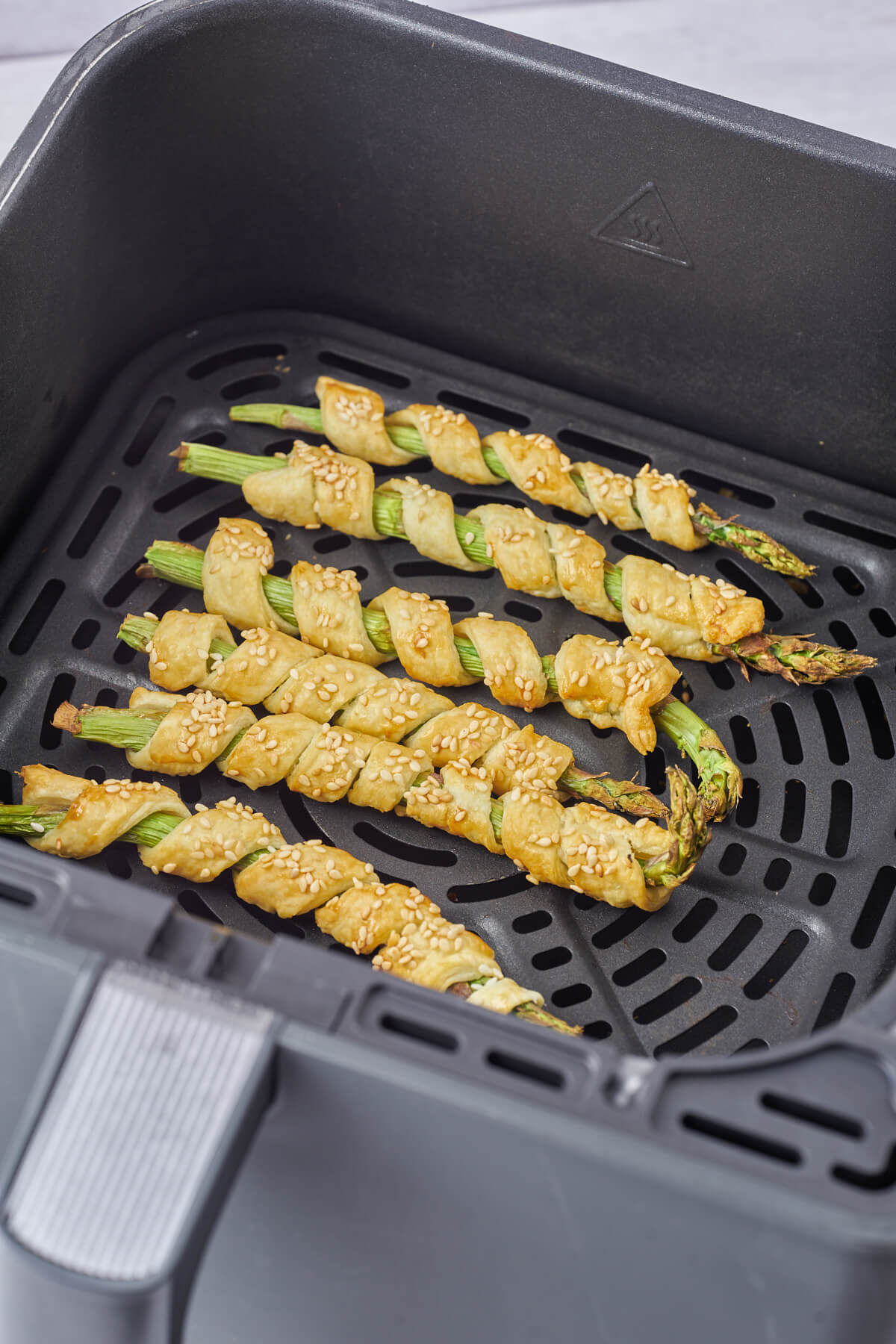 air fryer basket with asparagus wrapped in puff pastry